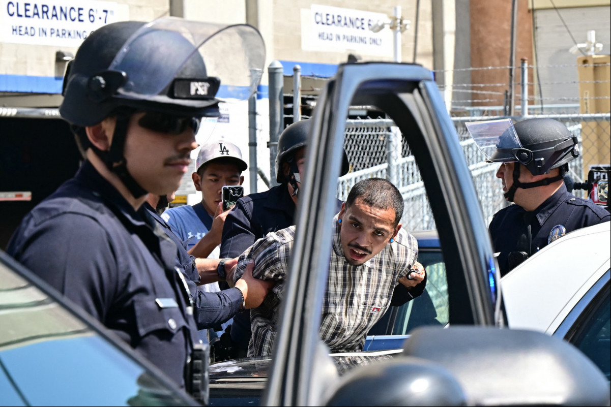 Um homem é detido pela polícia perto do Centro de Detenção Metropolitano (MDC), durante um protesto após operações federais de imigração, no centro de Los Angeles, Califórnia, em 8 de junho de 2025. O presidente dos EUA, Donald Trump, enviou 2.000 soldados em 7 de junho para lidar com a escalada de protestos contra as operações de imigração na região de Los Angeles, uma ação que o governador do estado classificou como 